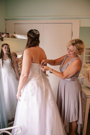 Final wedding dress adjustments being made in a bridal preparation room.