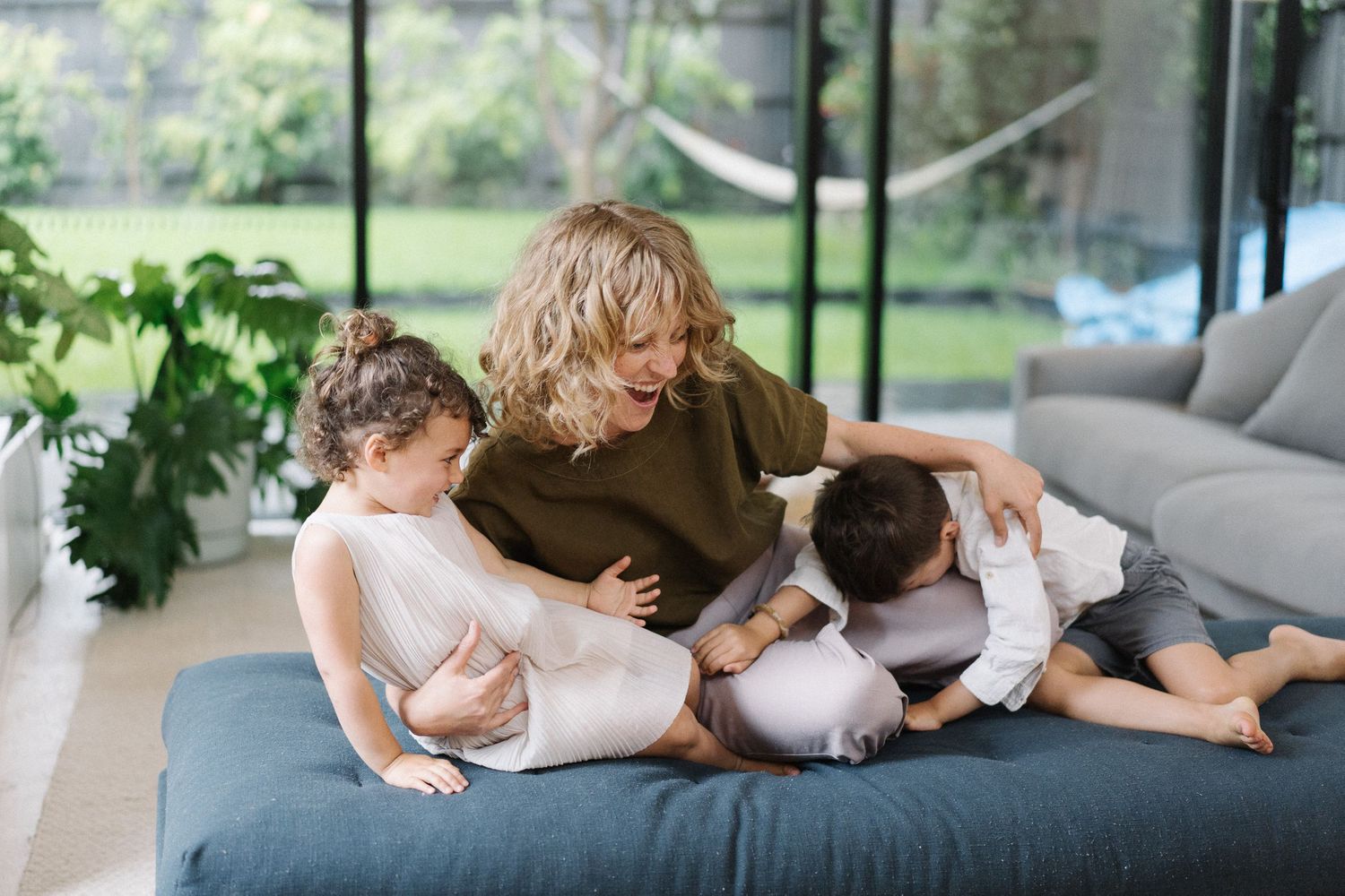 Mom and two children on the couch, playing and laughing together. Example of family photography by WhySoGeneric by Brandon.