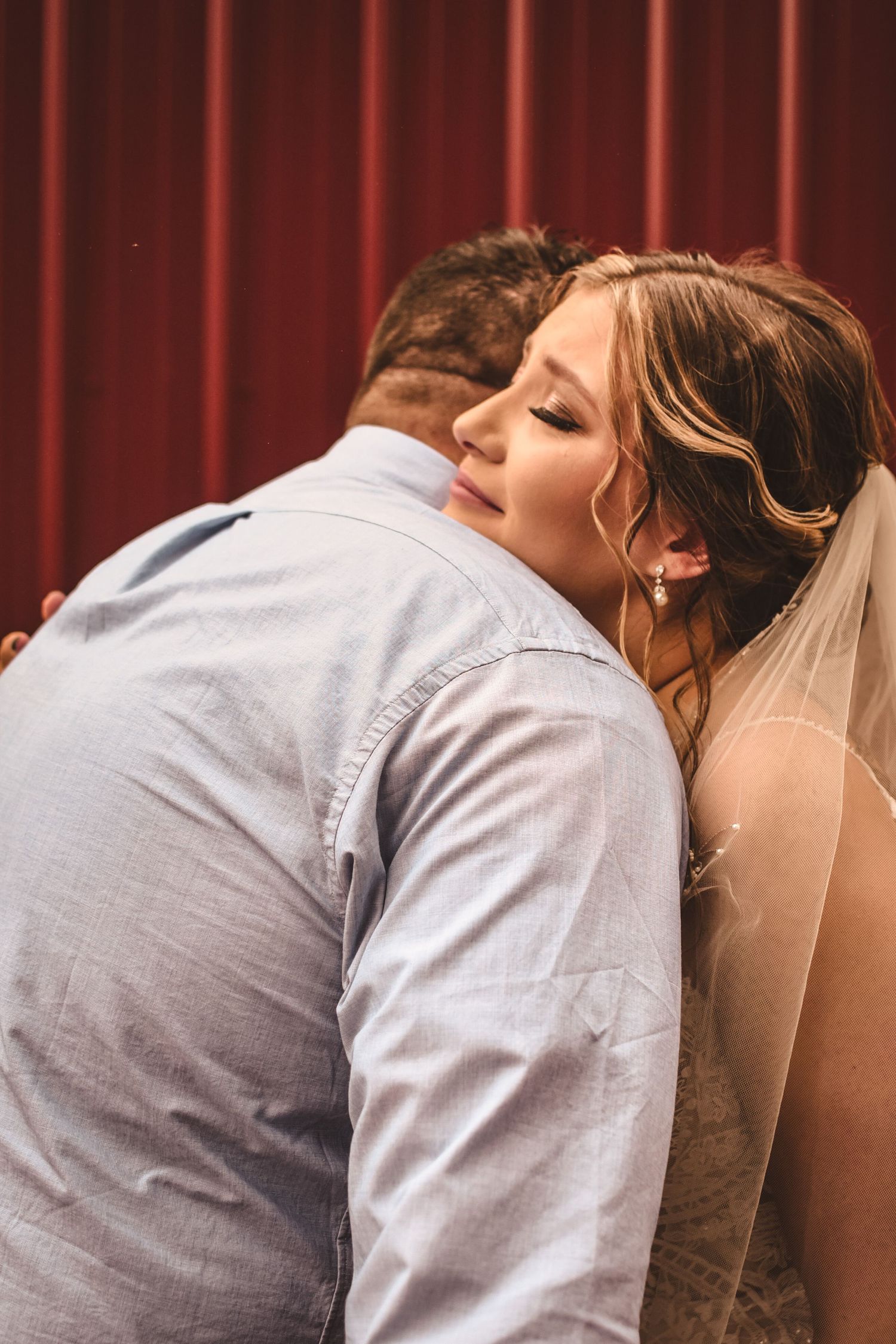 An intimate moment captured of a couple embracing against a red barn backdrop.