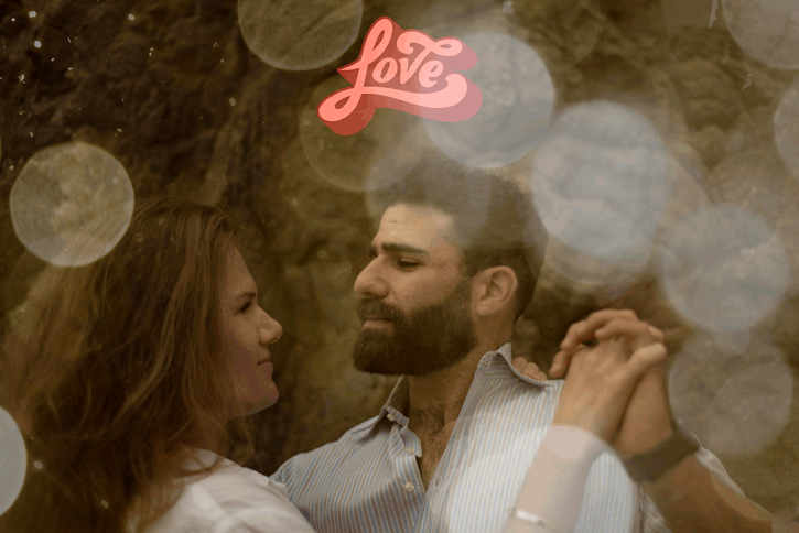 Romantic couple embracing under neon love sign with bokeh light effects.