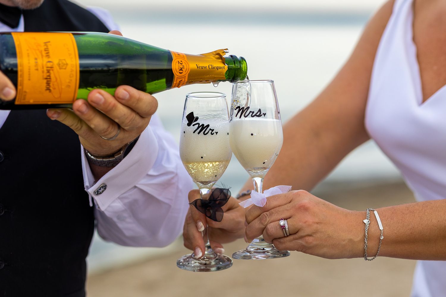 Champagne being poured into elegant personalized wine glasses against a blurred background.