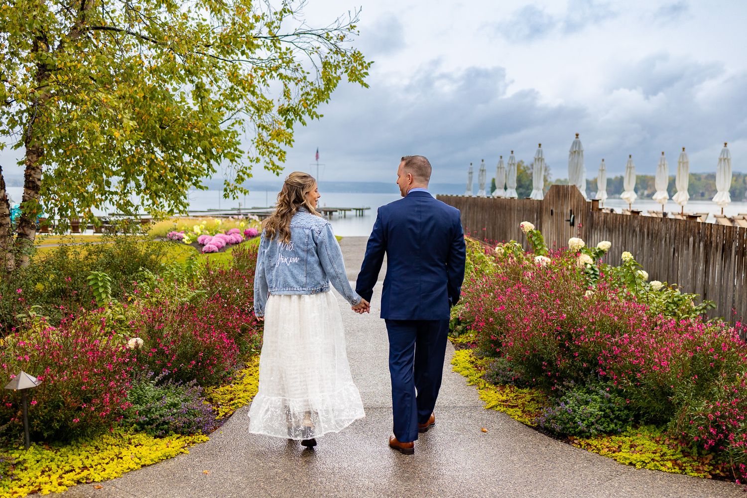 A couple walking through a garden path lined with colorful autumn flowers.
