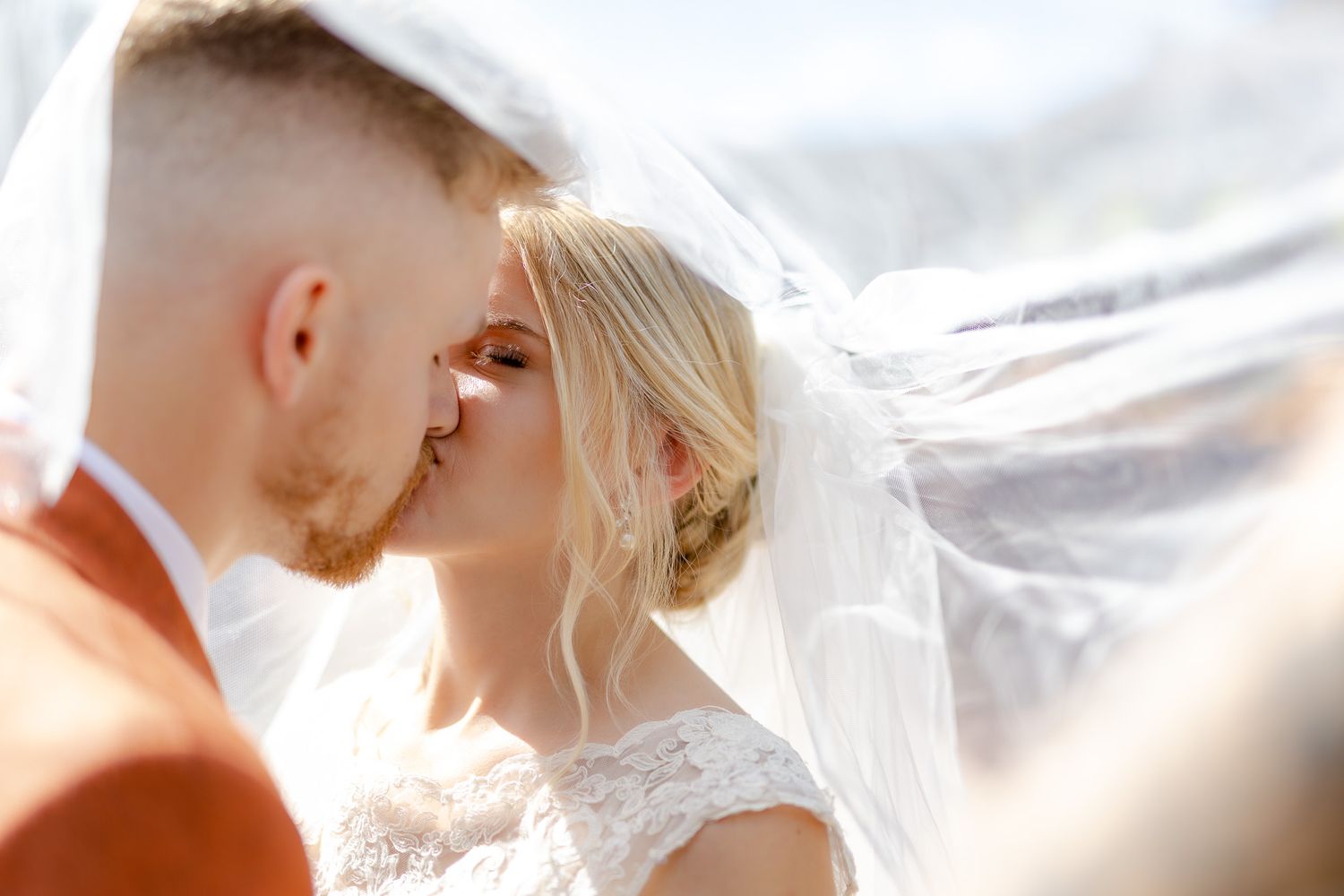 A bride and groom share an intimate moment under a flowing veil.