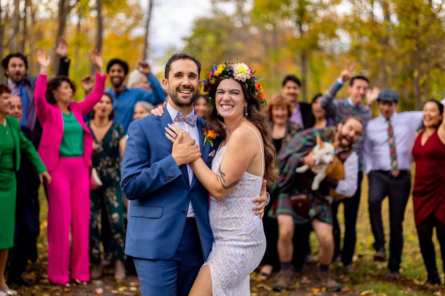 Wedding celebration in a fall setting with enthusiastic guests cheering in the background.