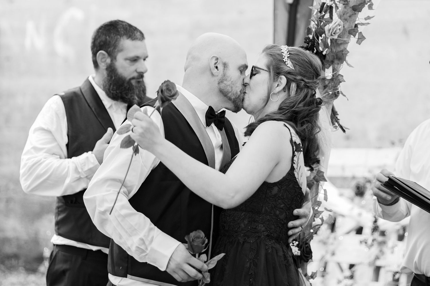A black and white photo of a couple sharing a playful moment with microphones.