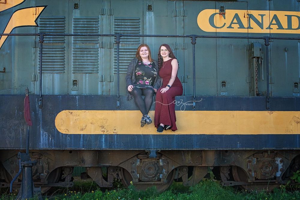Two people sitting on the side of a vintage Canadian railway car.