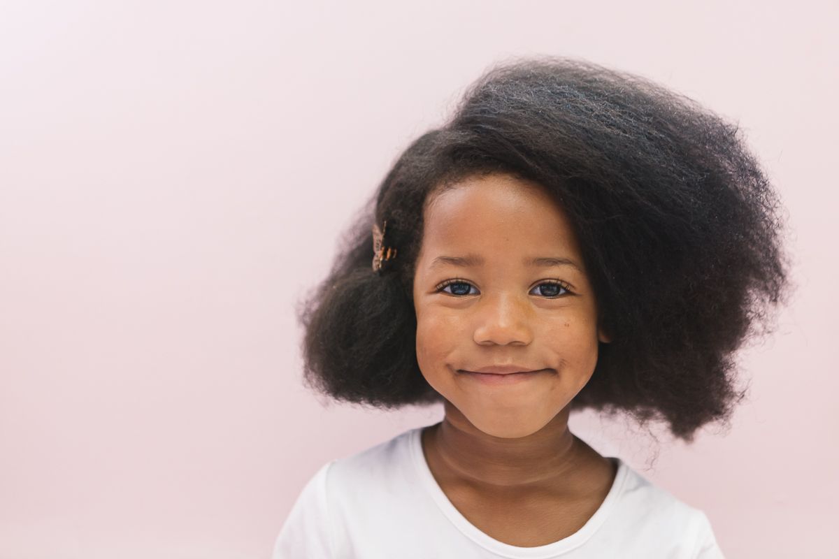 a close up of a black girl smiling against a pink backdrop during a birthday party session by NY Family Photographer Paula Brearley