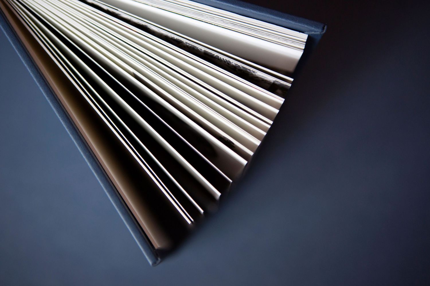 Close-up of fanned paper pages creating abstract lines against dark background.