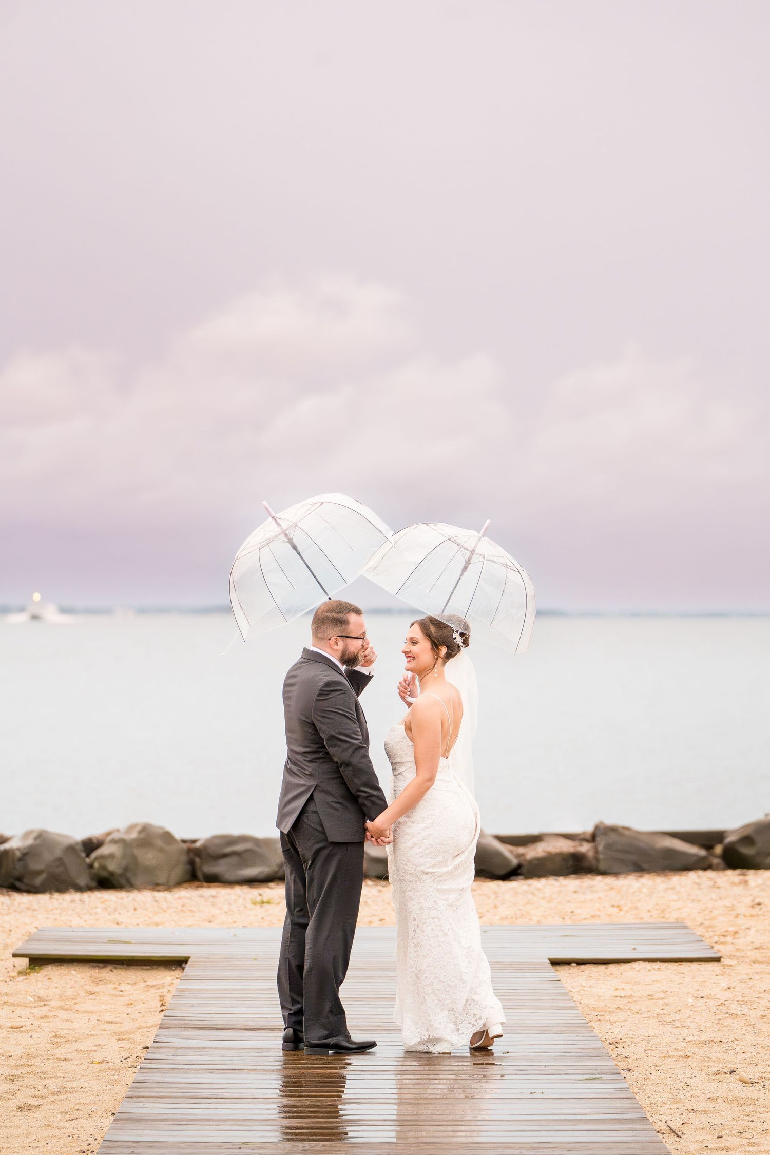Couple holding hands, backs to the camera, gazing into each other's eyes under their umbrellas.