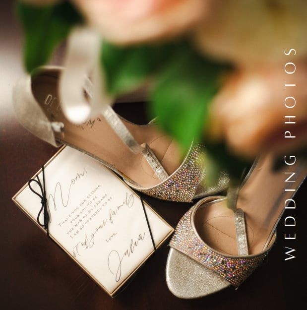 Sparkly wedding shoes next to an elegant invitation on blurred floral background.