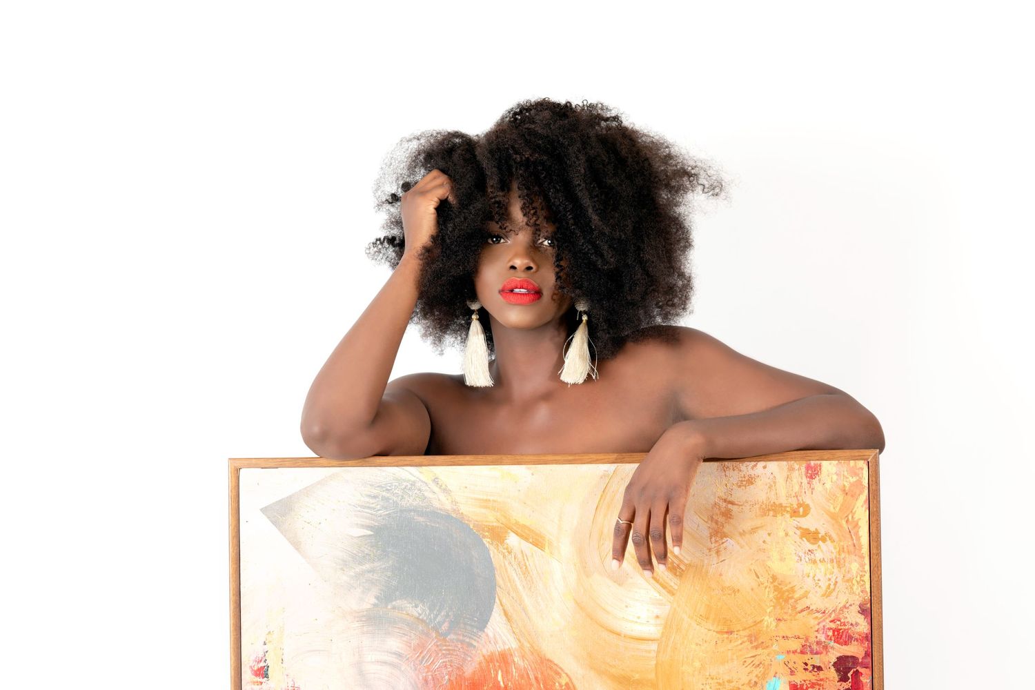 Portrait with natural afro hairstyle posing behind an abstract painted canvas.