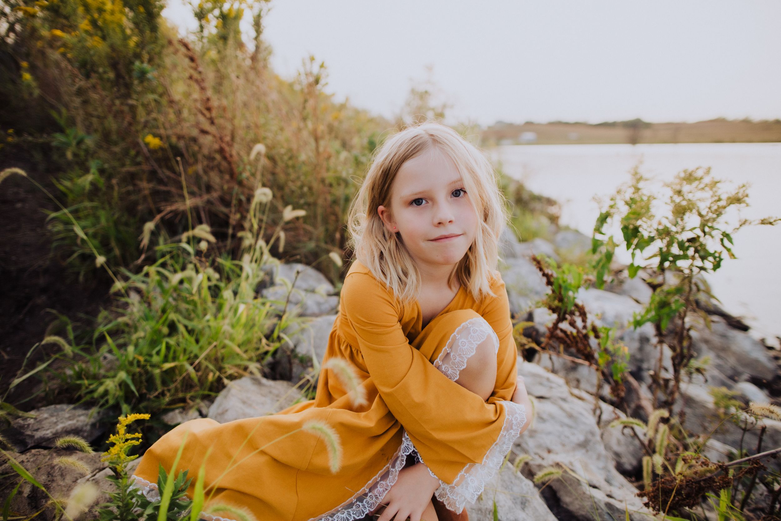A bright yellow dress stands out against a rocky natural landscape.