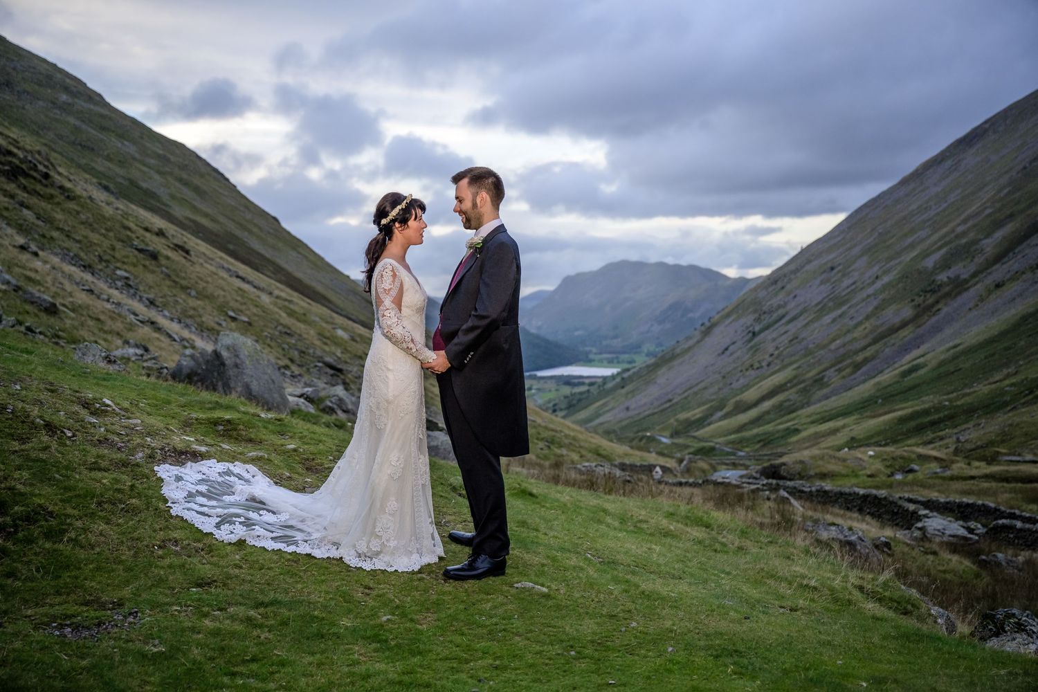 Bride and groom standing on Kirkstone Pass in the Lake District with the hills and Brothers Water in the background
