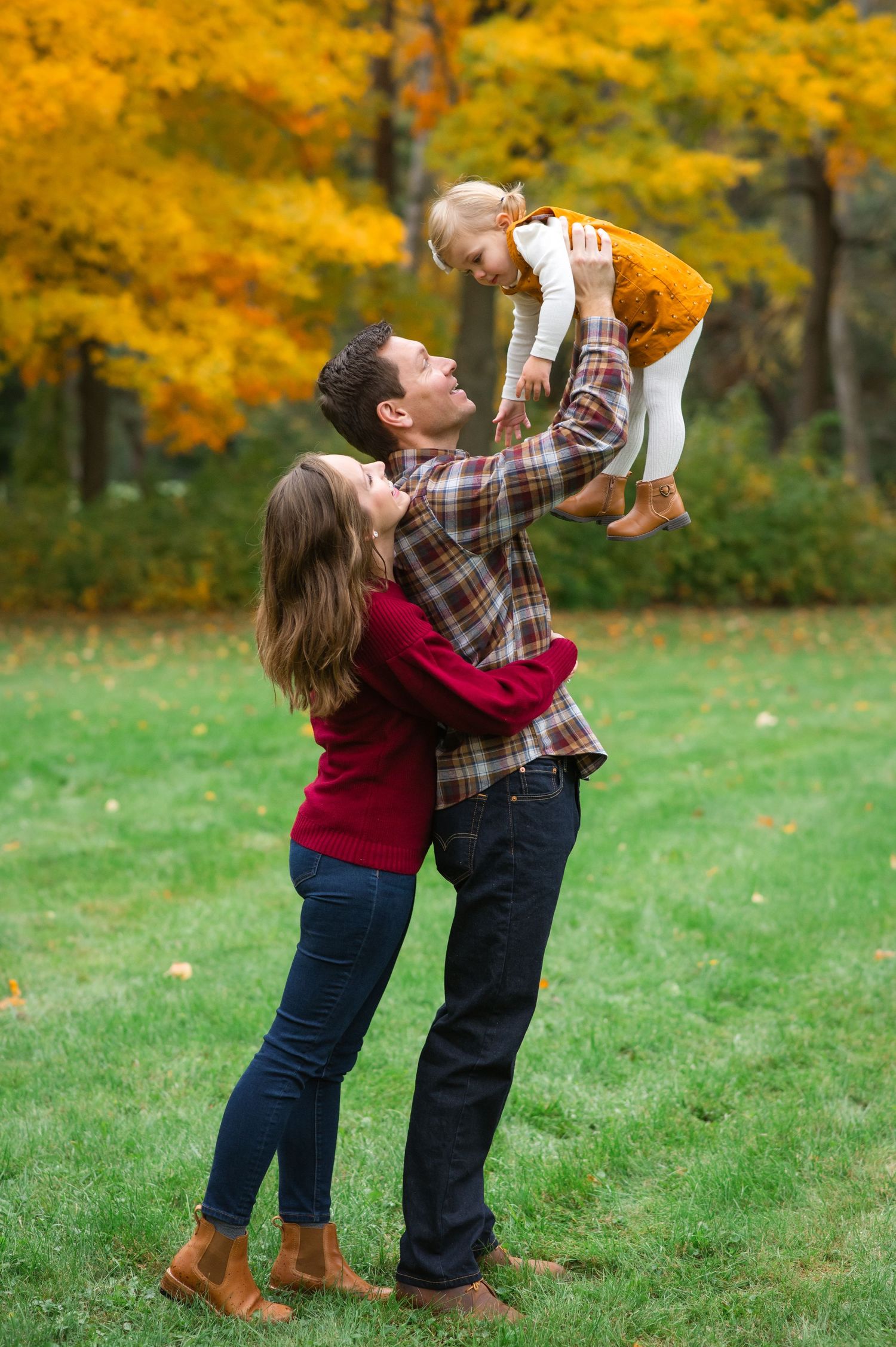 Family playing in autumn park with vibrant yellow foliage backdrop.