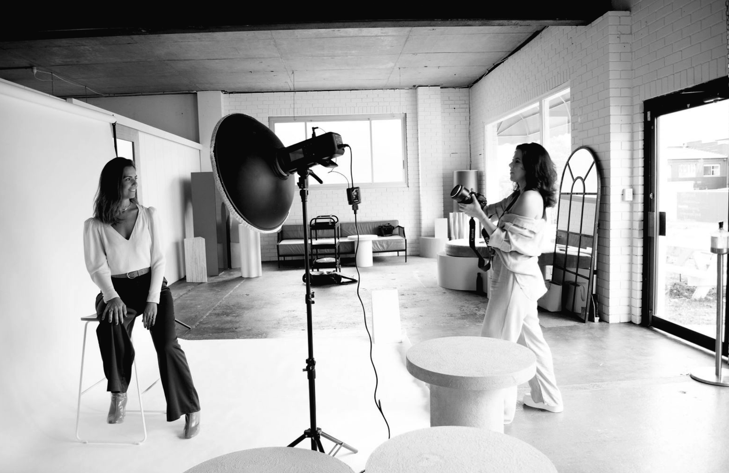 Behind the scenes photo of a photography studio setup with lighting equipment and white backdrop.