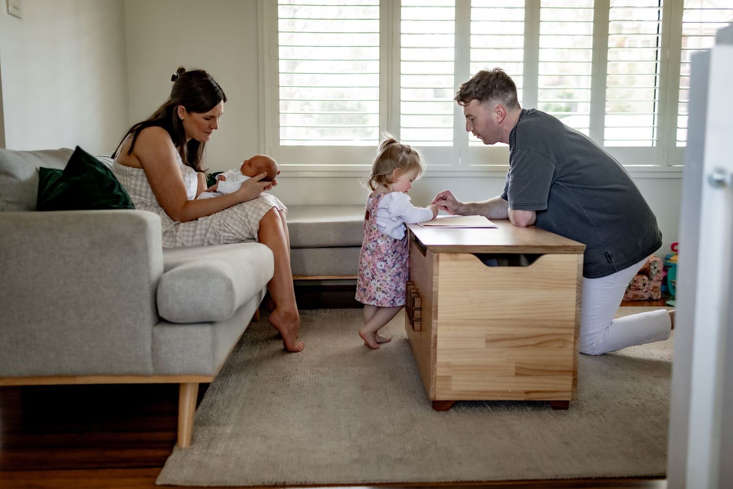 Family gathering around a wooden storage box in their contemporary living room.