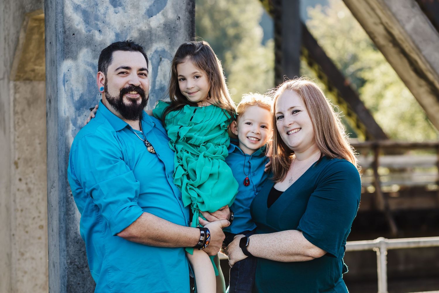 Family of four dressed in blue and green poses together for portrait.