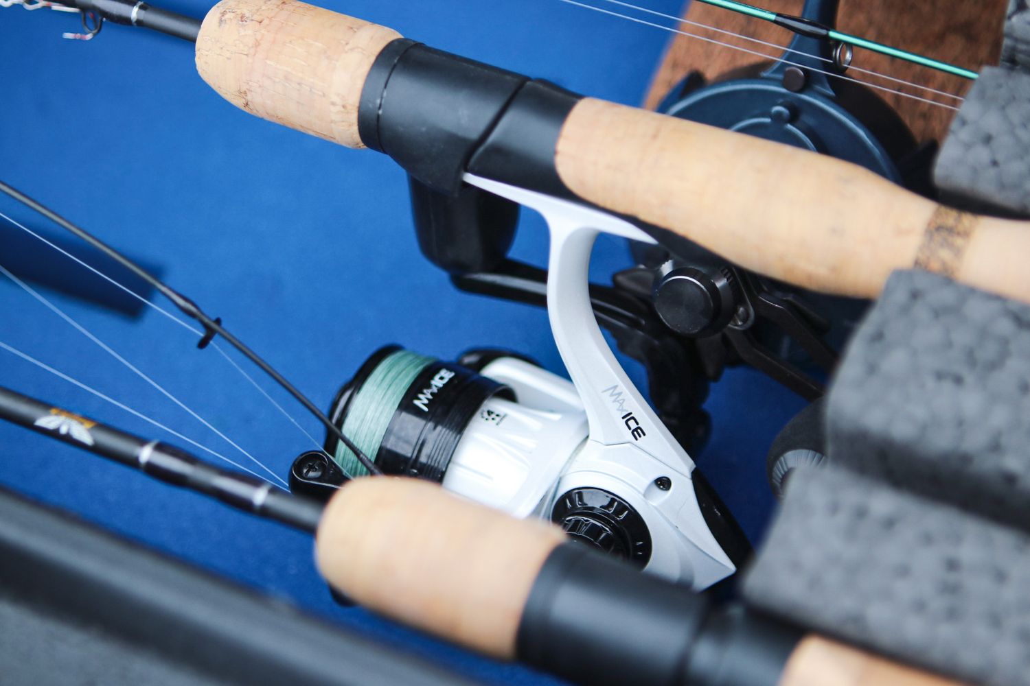 Close-up of fishing rod with cork handle and white spinning reel against blue background.