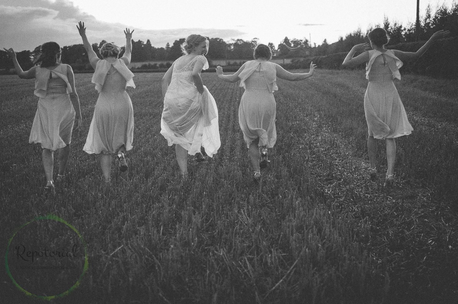 Reportage detail shot of bride and bridesmaids running through a field