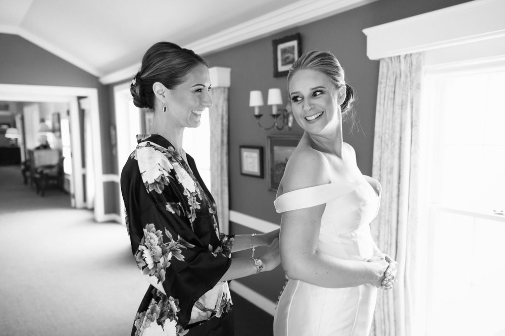 Bride and bridesmaid adjusting dress before wedding at Chagrin Valley Hunt Club in Ohio.