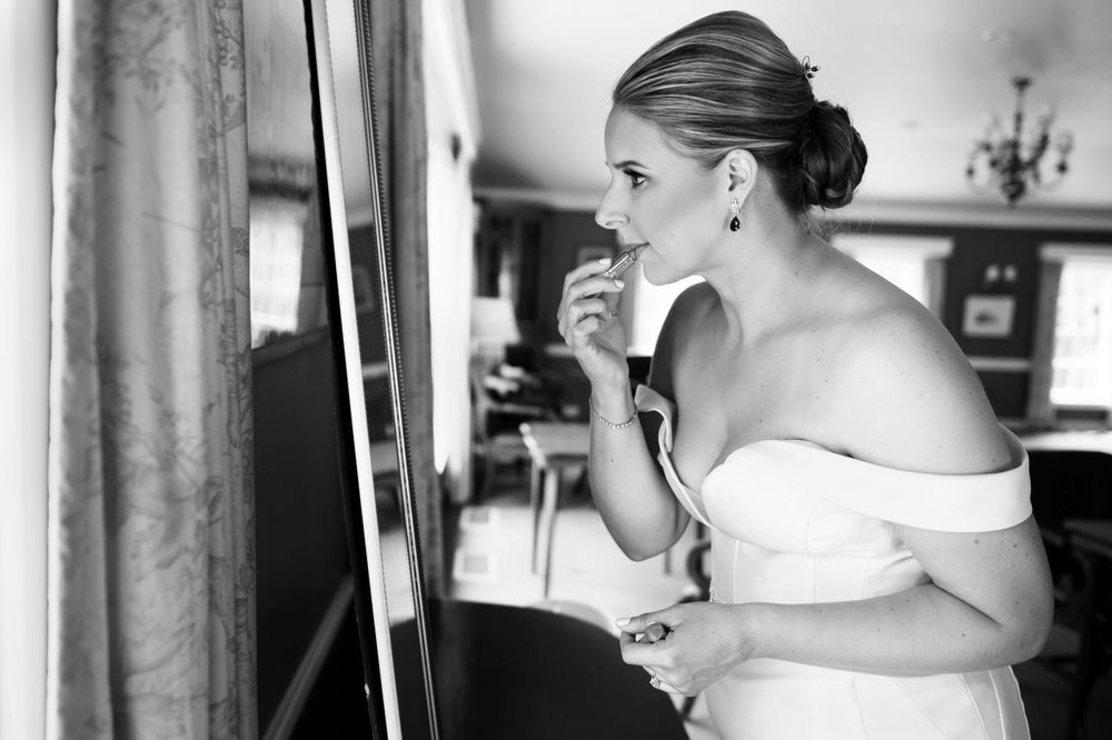 Bride applying lipstick before summer wedding at Chagrin Valley Hunt Club.