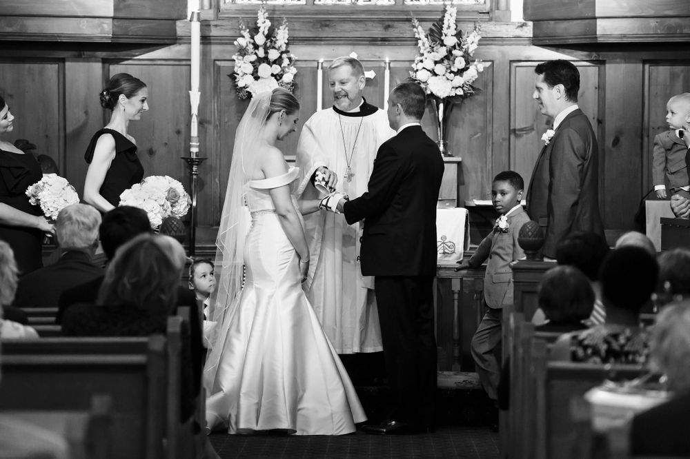 Bride and groom exchange rings during wedding ceremony at St. Huberts Episcopal Church in Kirtland Hills, Ohio.