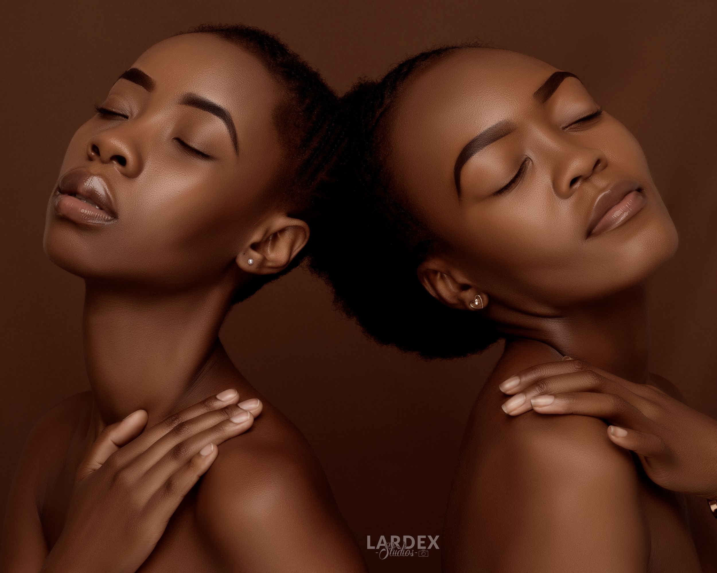 Artistic duo beauty portrait with models in serene poses against brown backdrop.