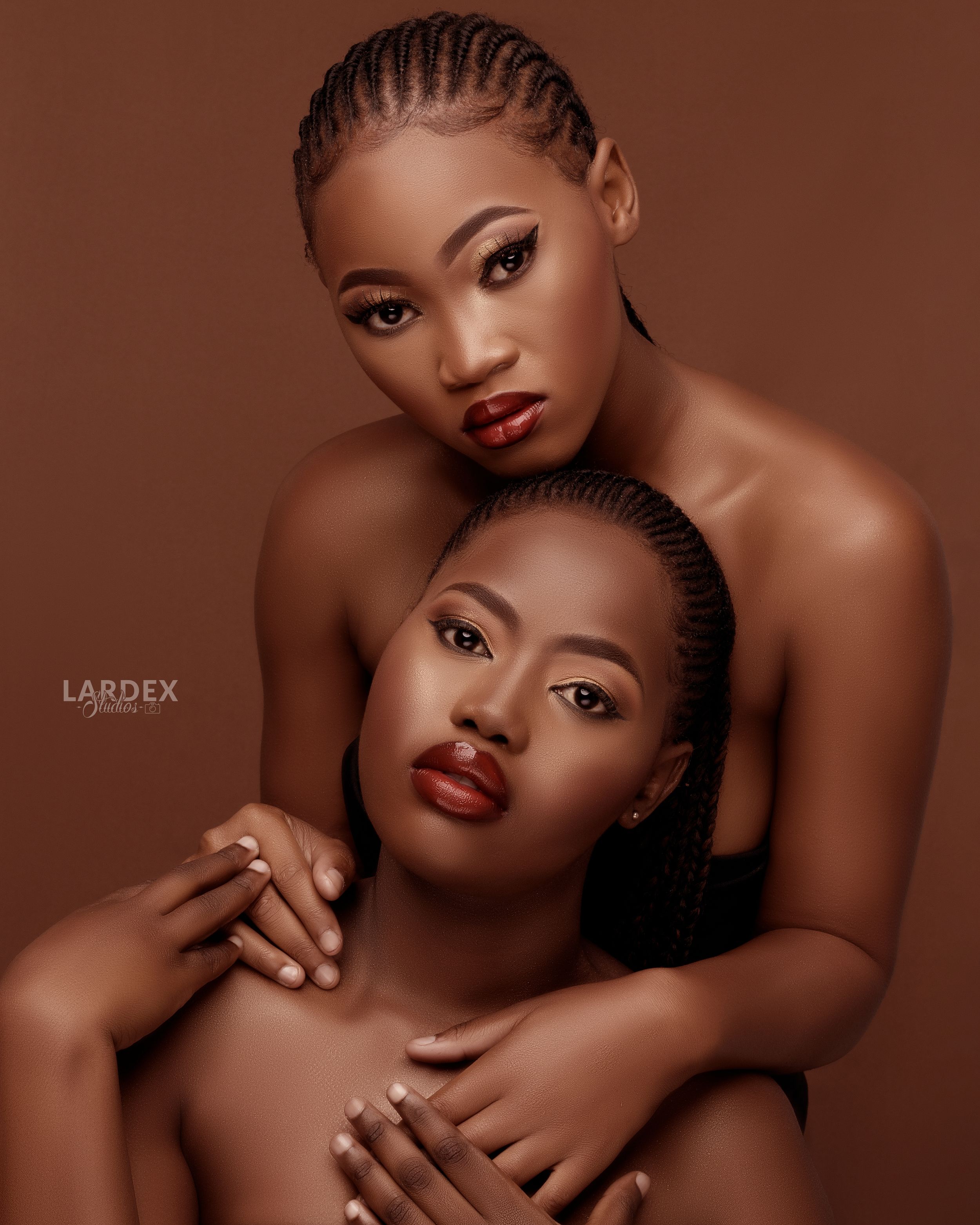 Artistic duo portrait showing intimacy and connection against warm brown backdrop.