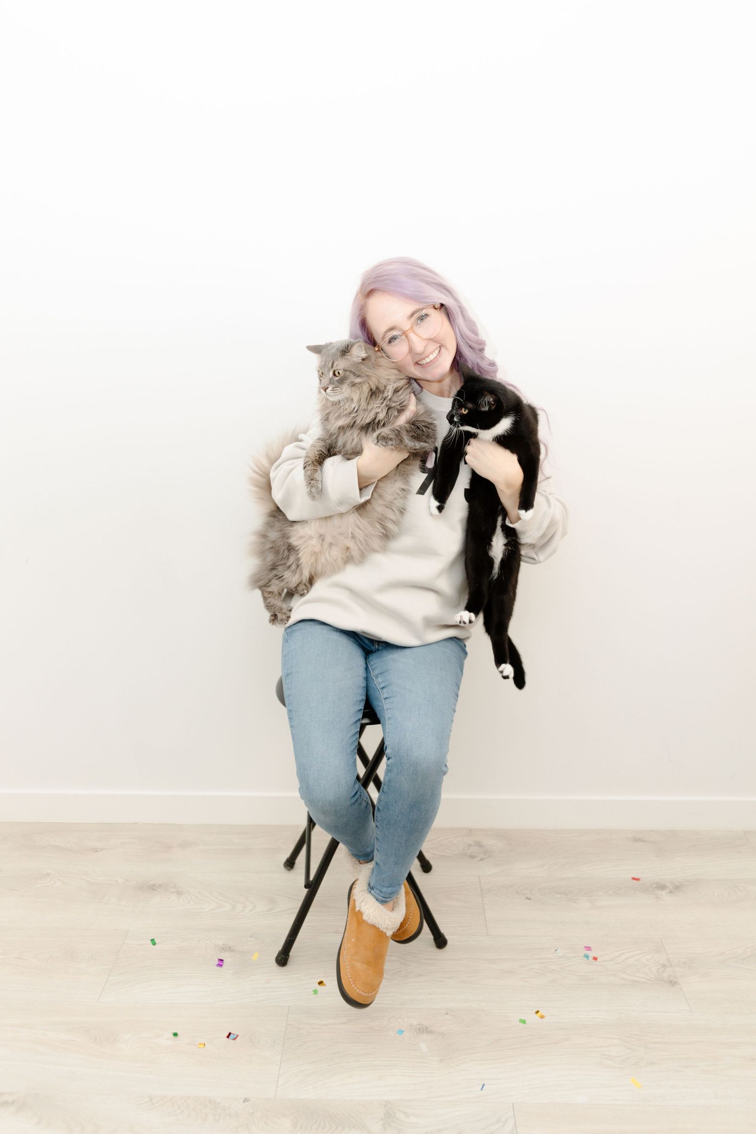 Brieanna sitting on a stool holding both Rogue and Rupert her 2 cats.