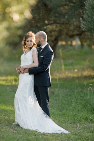 Elegant wedding portrait in a sunlit meadow with soft bokeh background.