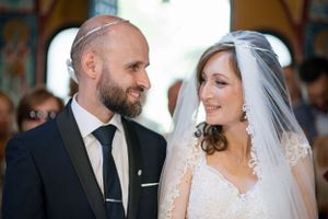 A joyful wedding portrait inside a decorative Orthodox church with colorful painted walls.