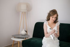 Bride sitting on dark green velvet sofa with modern decor in background.