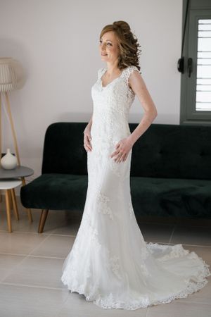 Full length view of lace wedding gown with chapel train in modern setting.
