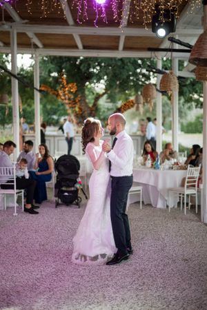 Romantic first dance at an outdoor wedding reception under twinkling lights and a covered pavilion.