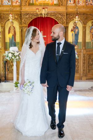 A wedding ceremony captured inside an Orthodox church with ornate gold iconostasis.