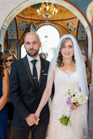 A wedding ceremony in a beautifully decorated Orthodox church with ornate details and chandeliers.