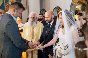 A traditional wedding ceremony in an ornate Orthodox church with the priest conducting the service.