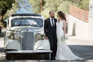 A classic vintage Mercedes wedding car serves as backdrop for a romantic outdoor portrait.