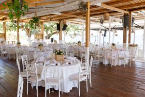 An elegant wedding reception venue with white tables and chairs under a wooden beam ceiling.