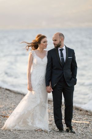 Windswept beach wedding portrait with waves and coastal scenery.