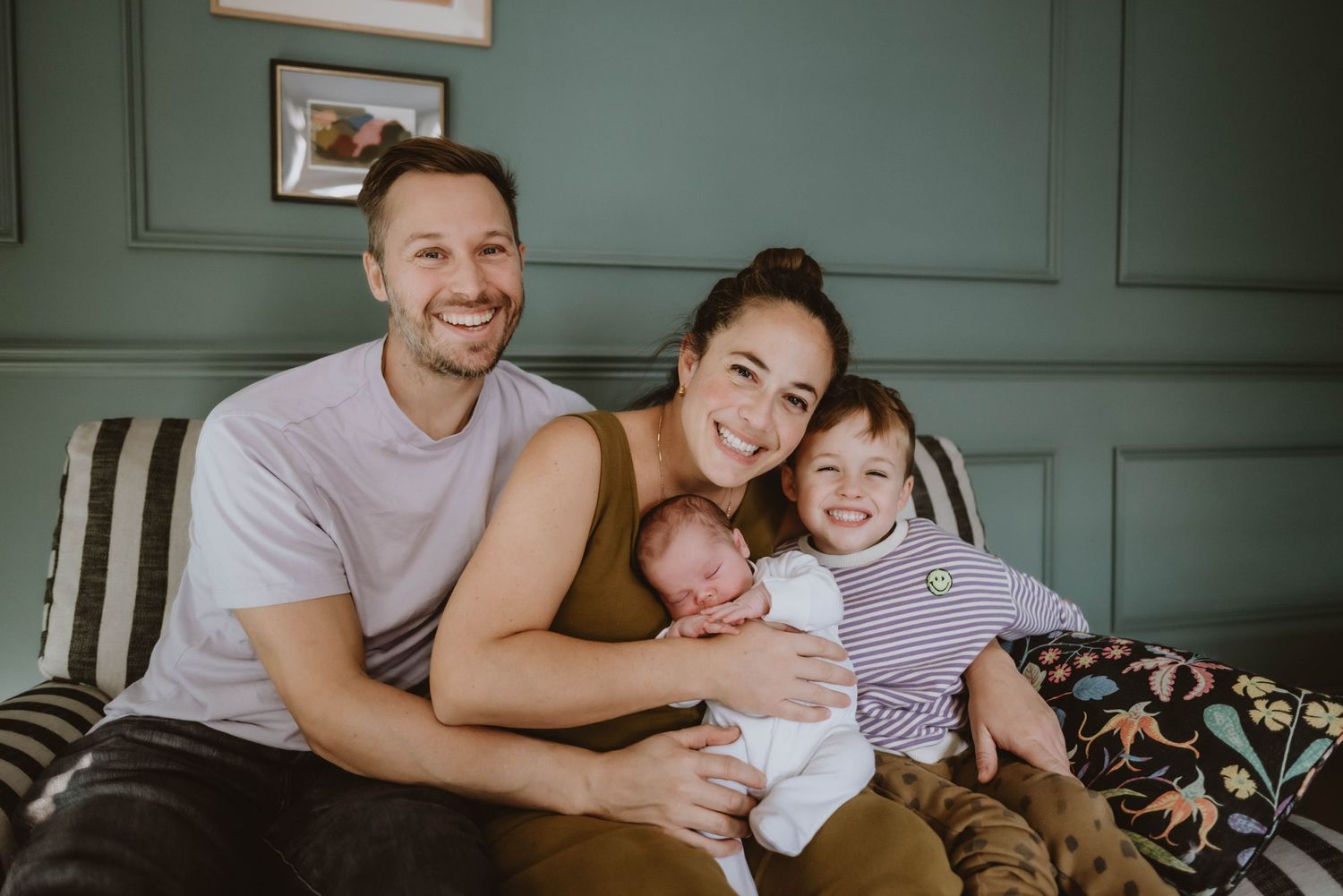 A happy family moment on a couch with parents and children sharing smiles together.