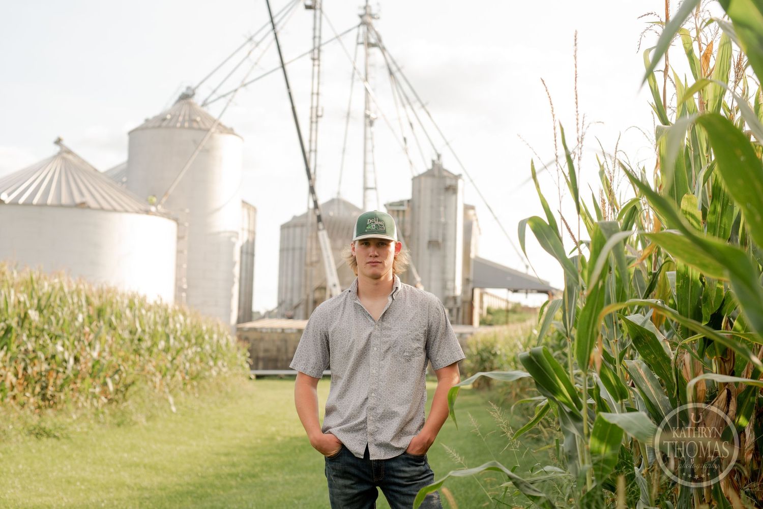 Rural farm scene with grain silos and corn stalks during golden hour.