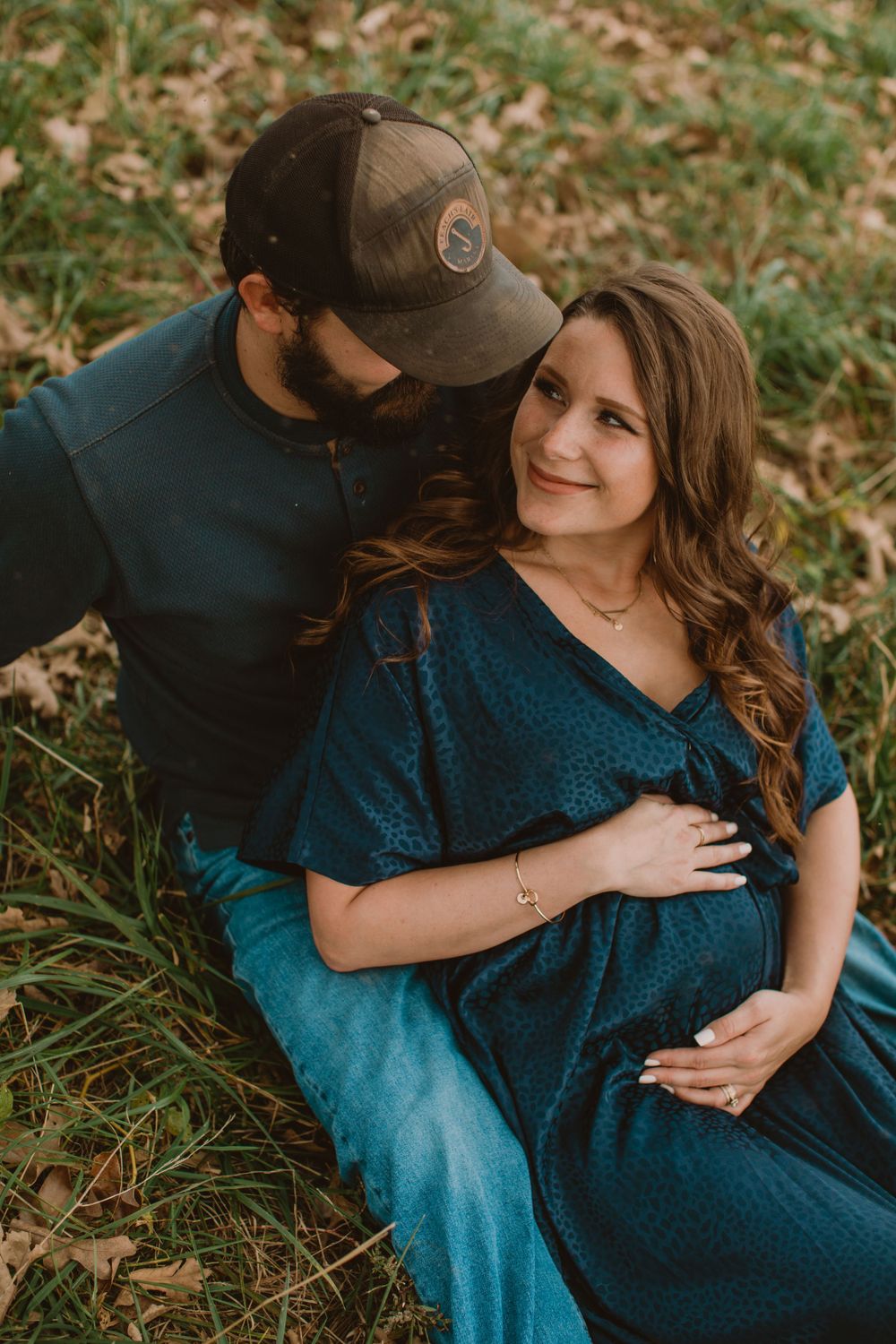 Couple in casual attire shares intimate moments on grass during autumn photoshoot.