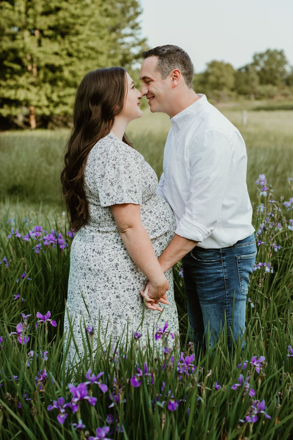 Couple poses together in field of purple iris flowers during spring photo session.