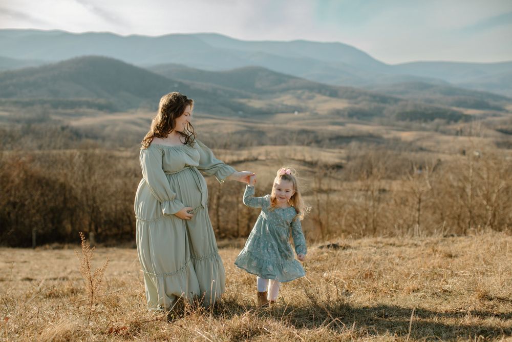 Mother and daughter holding hands while looking at mountain vista.