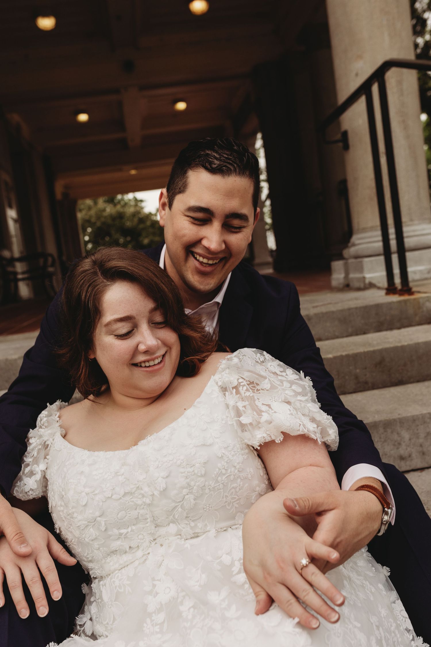 A joyful wedding couple sharing a tender moment on stone steps.