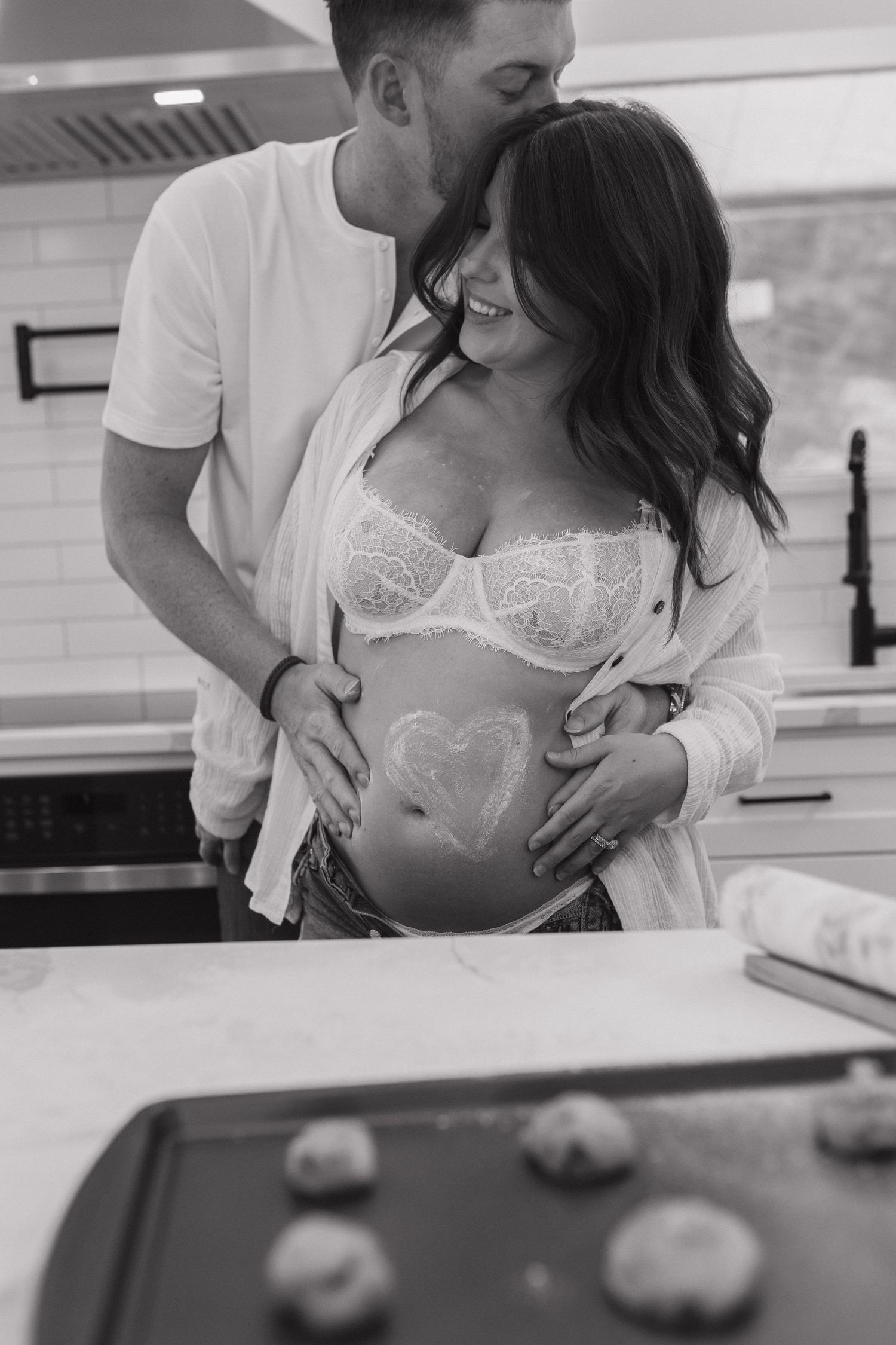 Black and white maternity photo showing a pregnant belly with a heart drawn on it.