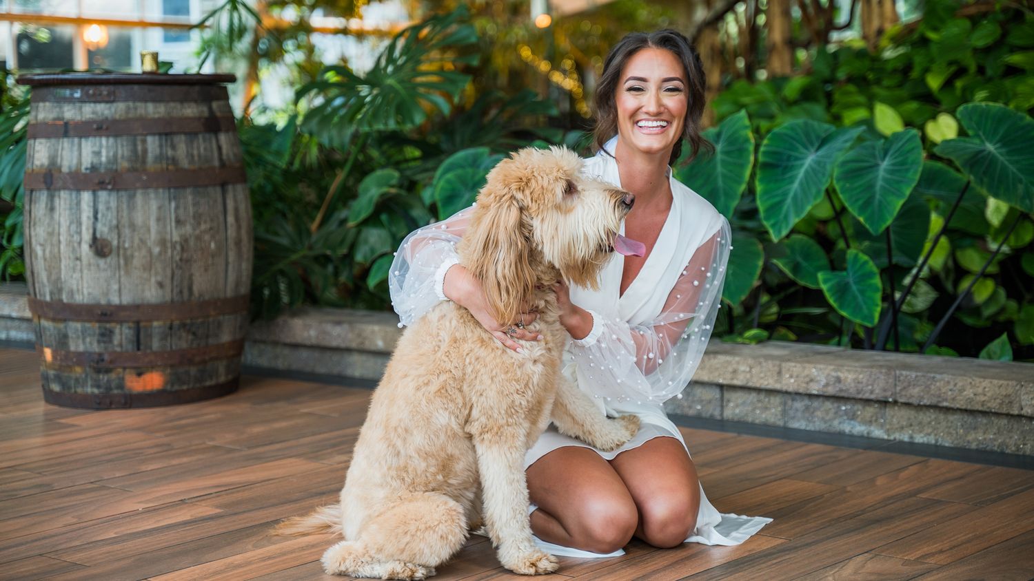 Bride hugs her dog in a white robe during getting ready.