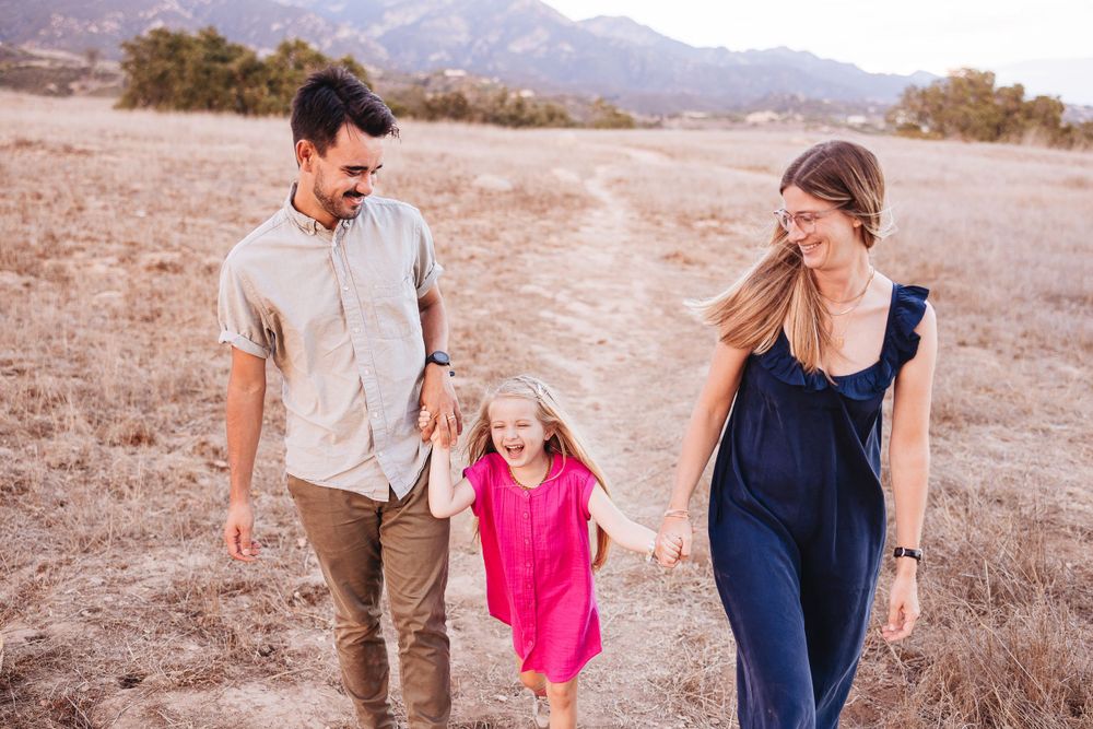 A family walks together through a desert landscape at sunset.