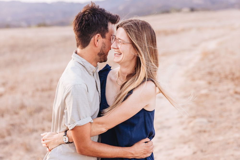 A romantic embrace captured in warm sunlight with mountains in the background.